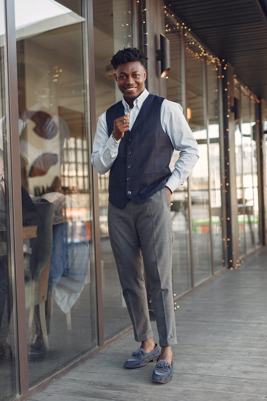 cheerful stylish black man in formal outfit and trendy loafers outside modern cafe